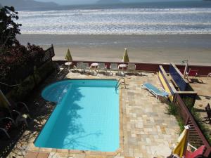 
a beach area with a pool and a beach chair at Pousada Casa na Praia in Ubatuba
