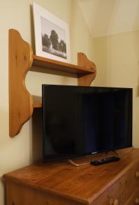 a flat screen tv sitting on top of a wooden entertainment center at One Pelham Grove Bed & Breakfast in Stocking Pelham