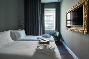 um quarto de hotel com duas camas e um espelho em O Artista Suites by Europe em Lisboa