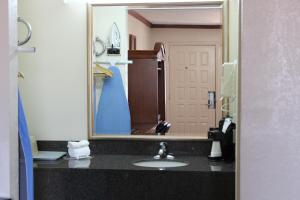 a bathroom with a sink and a large mirror at Sanger Inn in Sanger +4 photos