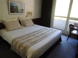 a large bed in a hotel room with a large window at Hôtel 4C in Cluses