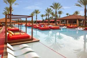 a large swimming pool with chairs and palm trees at Golden Nugget Lake Charles in Lake Charles