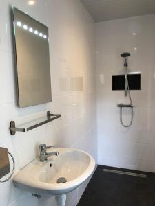 a white bathroom with a sink and a mirror at De goede verwachting in Kamperland