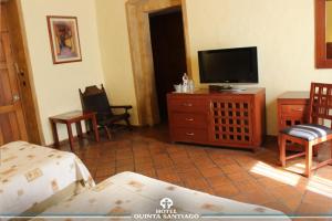 een woonkamer met een flatscreen-tv en een bed bij Hotel Quinta Santiago in Querétaro