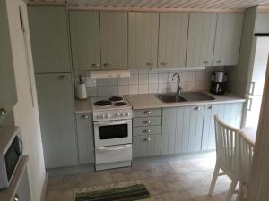eine Küche mit weißen Schränken, einem Herd und einer Spüle in der Unterkunft Holiday Home near Norrköping in Skärblacka