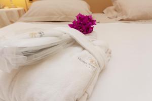 a white bed with a towel and a flower on it at Hotel Simius Playa in Villasimius