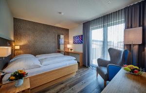 una habitación de hotel con una cama grande y una silla en Landgasthof Wurm, en Bogen