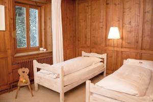 Duas camas num quarto com paredes de madeira e uma janela em Hotel Veduta em Cinuos-Chel