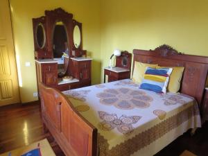 una camera con un grande letto in legno e uno specchio di Casa São João a São João da Serra