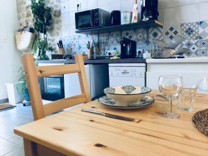 een keuken met een houten tafel met een kom en glazen bij La Marelle in Avrillé-les-Ponceaux
