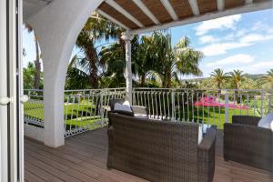a porch with chairs and a fence and palm trees at Hotel Simius Playa in Villasimius