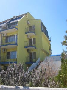 ソゾポルにあるGuest House Dimaの青いバルコニーと木々のある黄色い建物