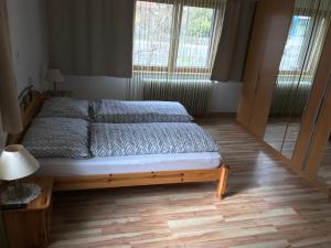 a bedroom with a bed with a wooden frame and two windows at Gästehaus Blümel in Köflach