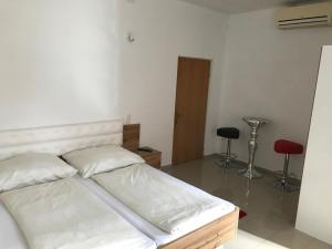 a bedroom with a bed with white sheets and two chairs at Gästehaus Blümel in Köflach