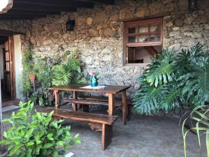 una mesa de madera y bancos frente a una pared de piedra en El Pajero de Erese en Erese