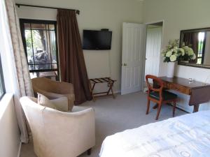 a bedroom with a bed and a desk and chairs at Three Gables B&B in Whakamarama