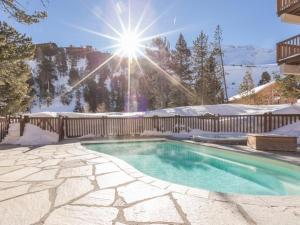 a swimming pool in the snow with the sun shining at Superbe appt 2 chambres Arc 1950 in Arc 1950
