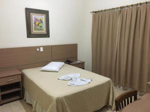 a hotel room with a bed with towels on it at Hotel Vila Rica in Alfenas