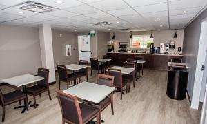 a dining room with tables and chairs and a kitchen at The Souris Hotel in Souris