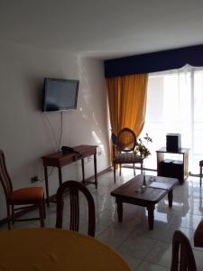 ein Wohnzimmer mit einem TV, einem Tisch und Stühlen in der Unterkunft Apart Antofagasta in Antofagasta