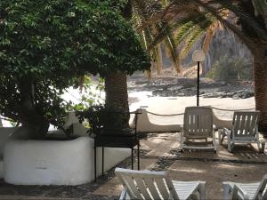 a group of chairs and a table and palm trees at Apartamento Playa Chica Tenerife in San Andrés