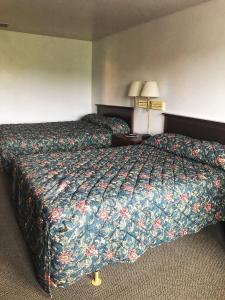 a hotel room with a bed with a floral bedspread at Neva Jean Motel in Marshfield