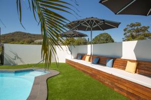 uma área de estar exterior com um guarda-sol e uma piscina em Hotel Nelson em Nelson Bay