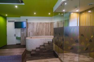 een badkamer met een bad en een televisie. bij Hotel y Villas Natura in Mexico-Stad