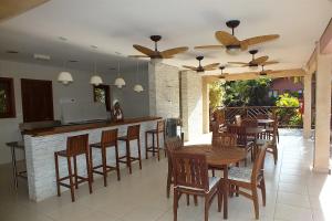 un restaurante con un bar con mesas y sillas de madera en Residencial Yacamim B39, en Ilhabela