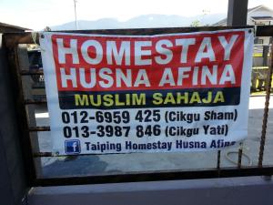 a sign hanging on a fence in front of a building at Taiping Homestay Husna Afina in Taiping