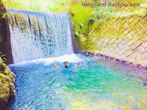 Ein Mann schwimmt in einem Becken vor einem Wasserfall in der Unterkunft Vanguard Backpackers in Sagamihara