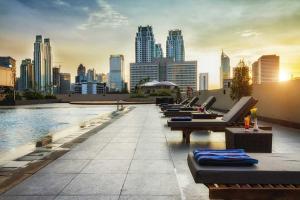 een zwembad op het dak met ligstoelen en een skyline van de stad bij Royal Kuningan in Jakarta