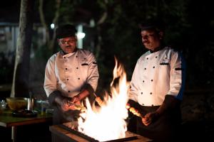 two chefs standing in front of a grill with fire at Ama Plantation Trails, Chikmagalur in Chikmagalūr