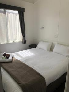 um quarto com uma grande cama branca e uma janela em Geelong Surfcoast Hwy Holiday Park em Mount Duneed