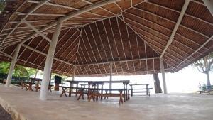 a group of tables and chairs under a straw roof at Ten RooMs in Telukbakau