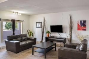 sala de estar con muebles de cuero y TV de pantalla plana en Motel 75 Monroe, en Monroe