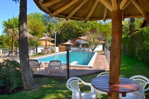 Una mesa y sillas bajo una sombrilla de madera cerca de una piscina. en Cabañas Los Duendes, en Villa General Belgrano