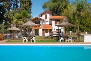 a house with a table and chairs and a pool at Cabañas Los Duendes in Villa General Belgrano