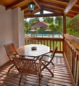 una terraza de madera con mesa y 2 sillas en Cabañas Los Duendes en Villa General Belgrano