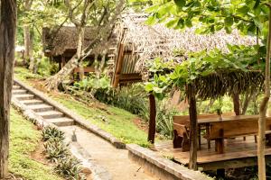 a wooden table and a bench in a garden at Cocobolo Beach Boutique Hotel in San Juanillo