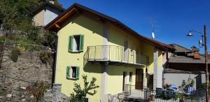 een geel huis met een balkon aan de zijkant bij cà dà Pina in Trarego