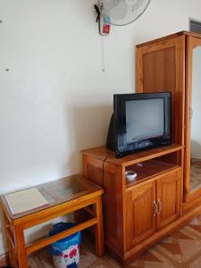 einen TV auf einem Holzständer mit einem Tisch und einem TV in der Unterkunft Nhà nghỉ Minh Hạnh in Hoàng Ngà