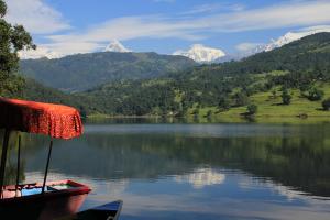 a boat on a lake with mountains in the background at The Begnas Lake Resort & Villas in Pokhara