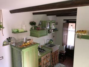 una cucina con armadi verdi e lavandino di Al castello San Piero Patti a San Piero Patti