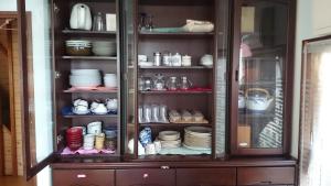 a cabinet filled with plates and cups and dishes at Guest house Minna no Ie in Achi