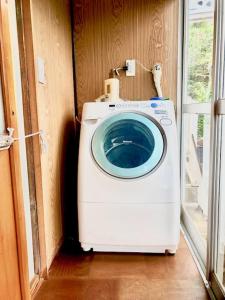 a washing machine in a corner of a room at Obasute Guesthouse Nakaraya in Chikuma
