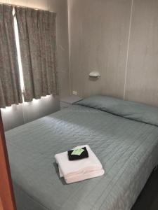 a bed with a pillow on top of it next to a window at Geelong Surfcoast Hwy Holiday Park in Mount Duneed