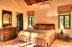 Un dormitorio con una cama, una cómoda y ventanas. en Hacienda Barrigona, en Sámara