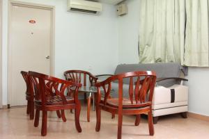 a dining room with four chairs and a table and a couch at Town Inn Hotel in Jerantut