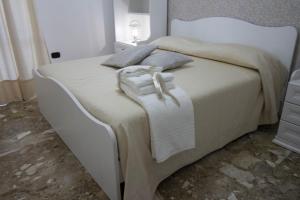 uma cama com lençóis brancos e almofadas em B&B ARENA em Pompeia